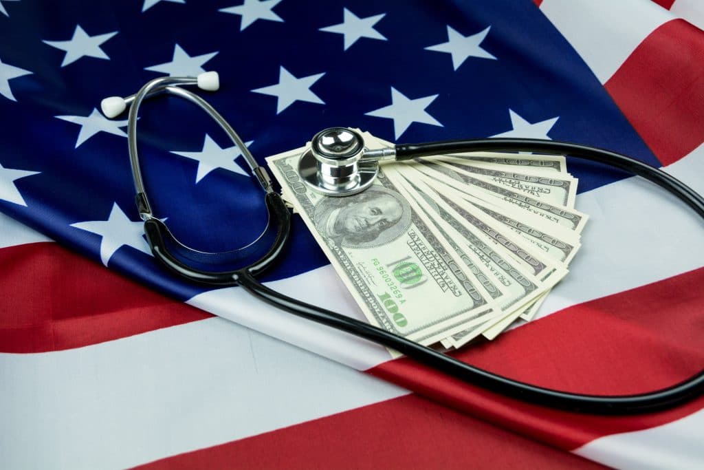 cash and stethoscope laying on american flag