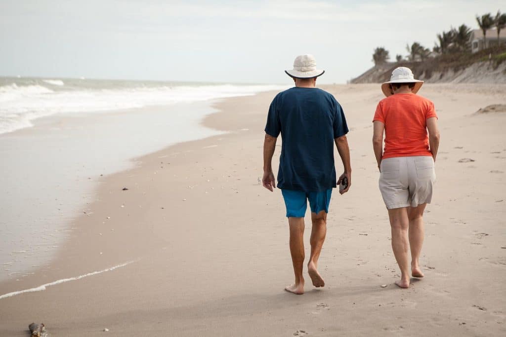 A middle-aged couple walks together along the beach.
