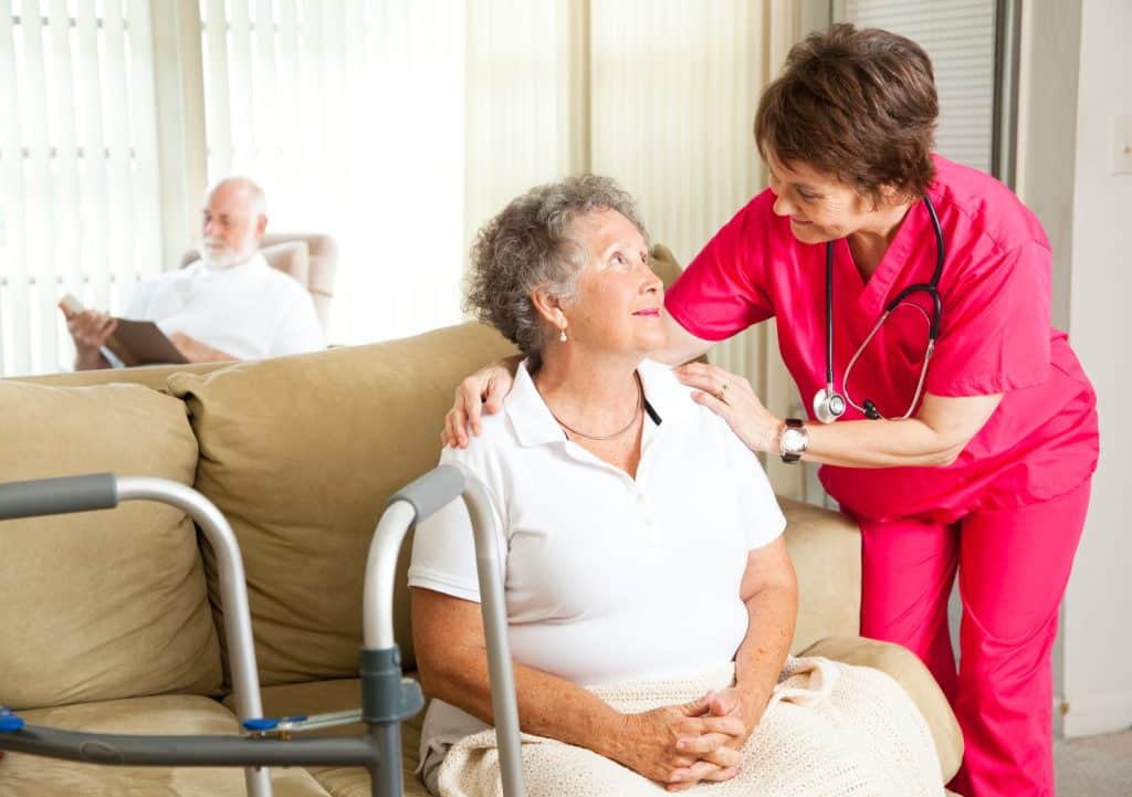A nurse at an assisted living facility helping an elderly woman.